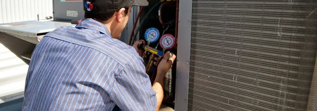 HVAC technician servicing a condenser unit in Henryetta