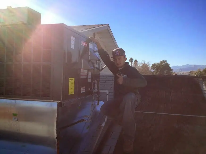 HVAC technician performing AC Tune-Up on a rooftop unit in Henryetta